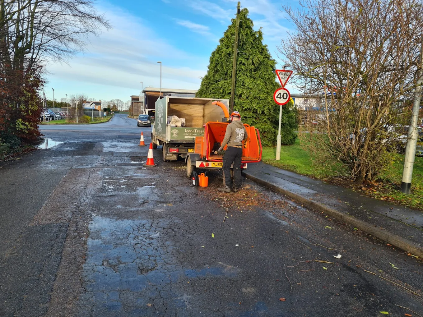 Worker operating a wood chipper on a street